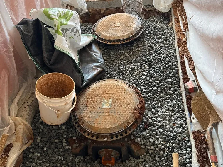 Two-compartment grease interceptor access lids set in a gravel bed