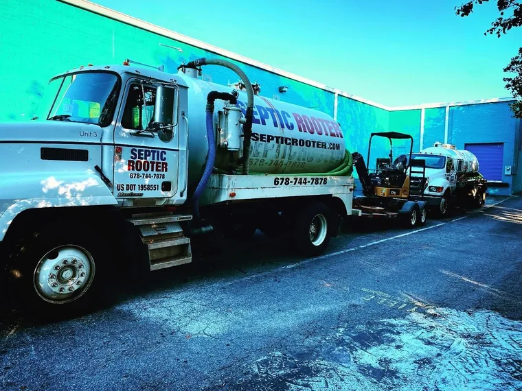 SepticRooter pump trucks and a mini-excavator staged for a job