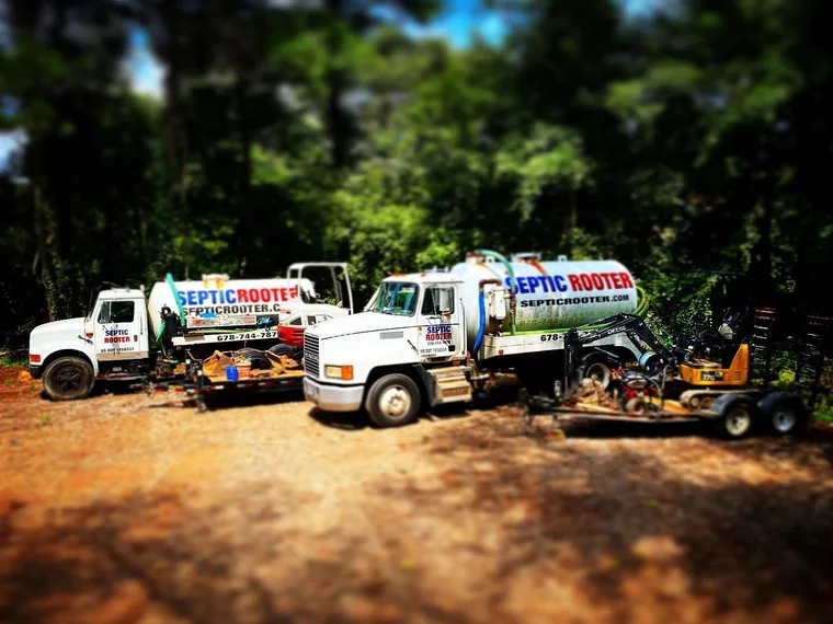 Two SepticRooter pump trucks and a mini-excavator at the yard