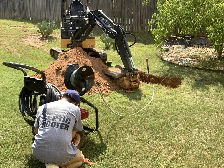 SepticRooter technician operating excavator to locate a septic tank