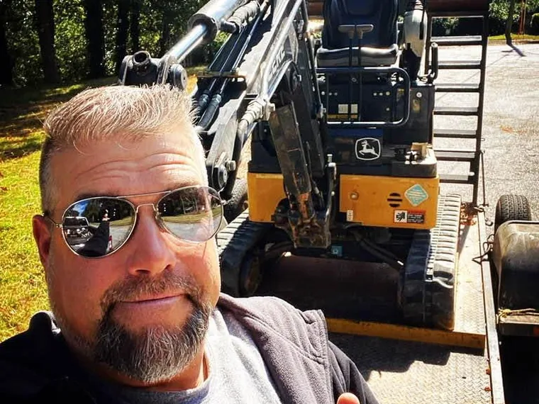 Rob Simmons selfie in front of SepticRooter excavator on trailer