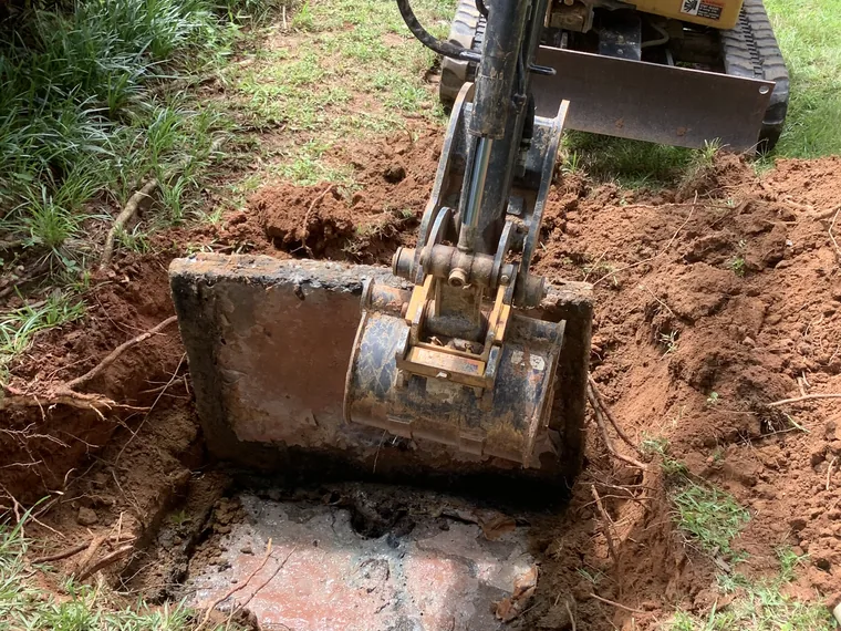 SepticRooter excavator digging to access a septic tank