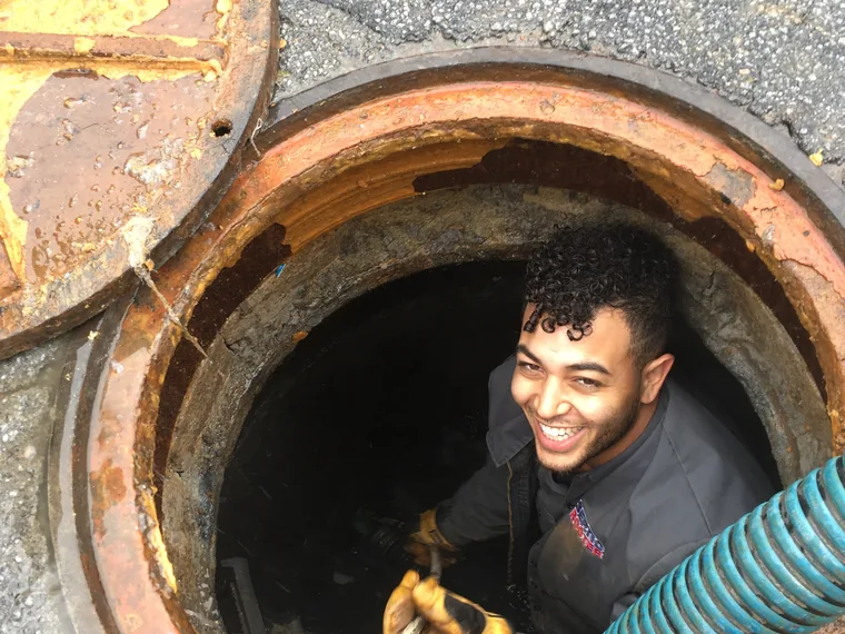 SepticRooter technician inside a septic tank riser inspecting the system