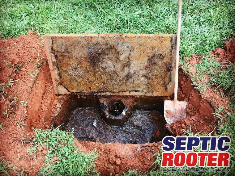 Excavated septic tank with the lid opened for repair access